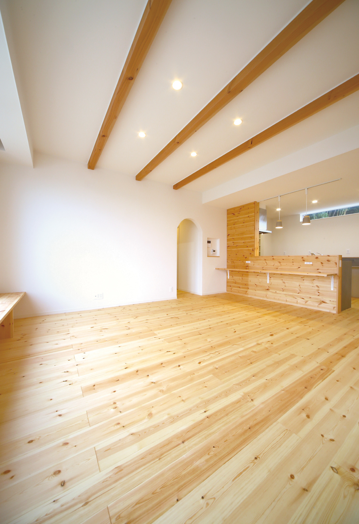 木の床とあらわし梁がつながる室内。